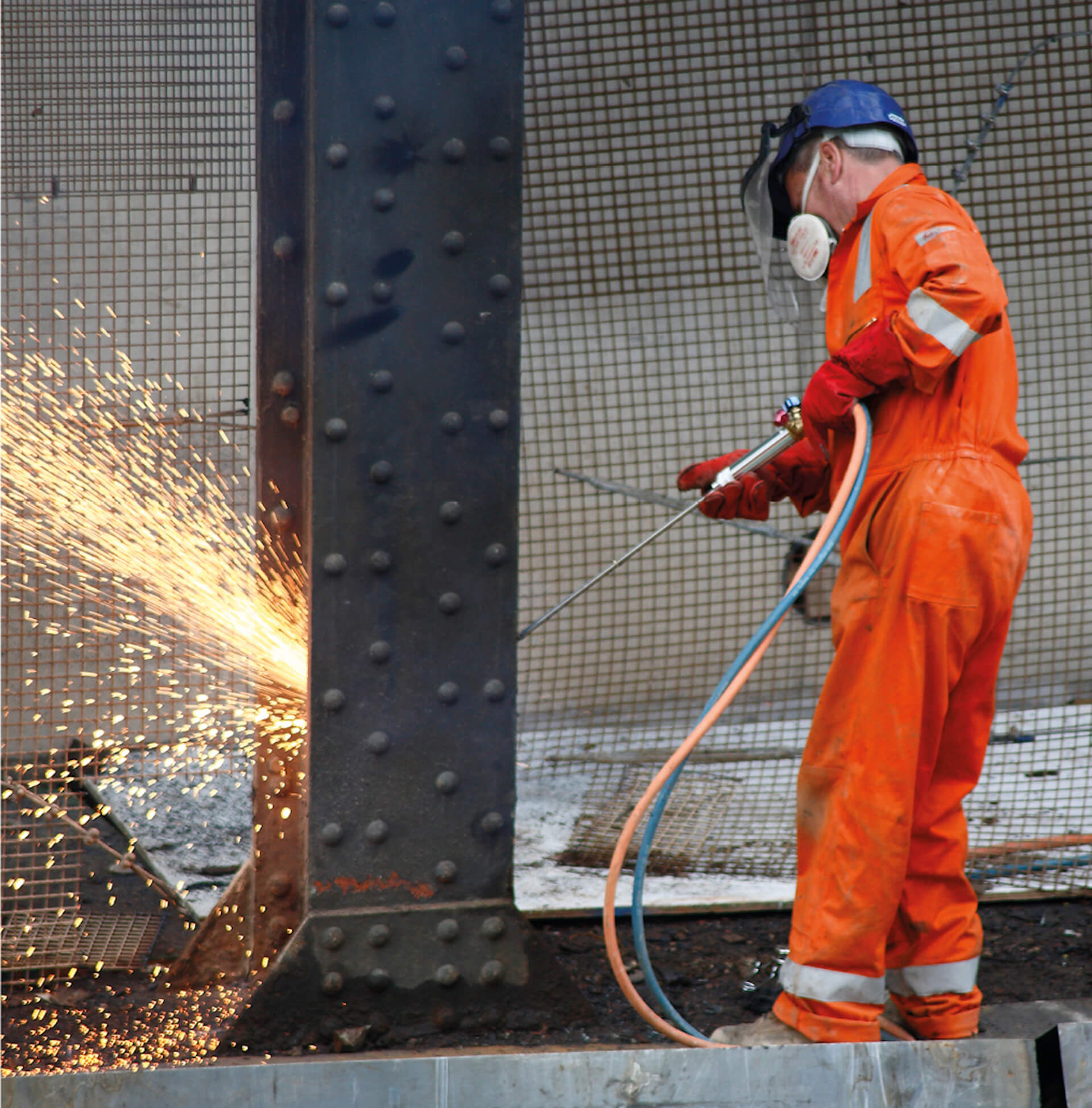 worker is carrying out hot cutting works to a steel Girder. Worker is wearing high visibility protective wear
