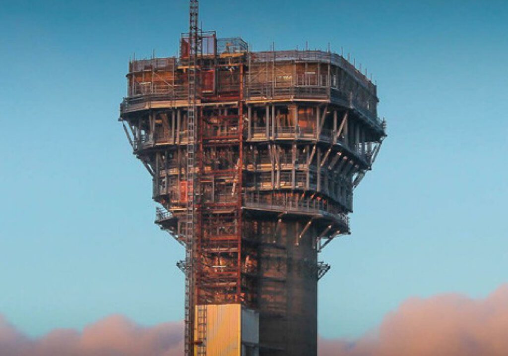 Image of the top quarter of 125 meter chimney located at Sellafield nuclear station. The Chimney has temporary works structures in place including steel structural propping.
