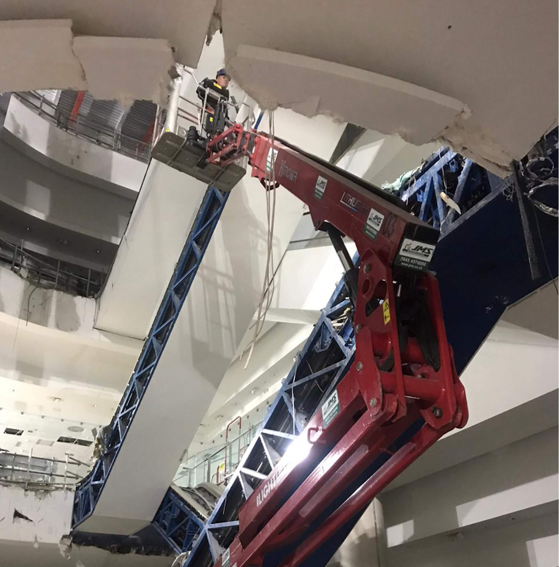 man on crane lift in centre of department store floors.