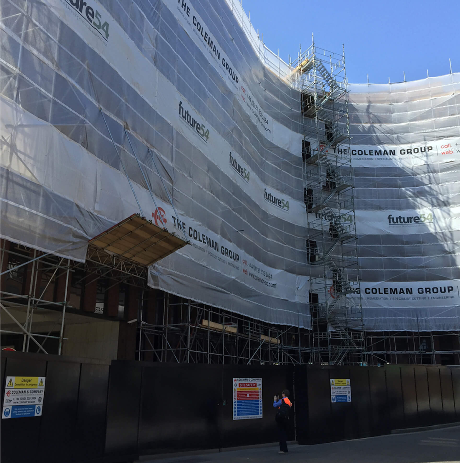 Building ready to be deconstructed showing temporary hoarding to the front of it, scaffolding with protective sheeting on it with The Coleman Group Branding. Temporary staircase installed to the centre of the building