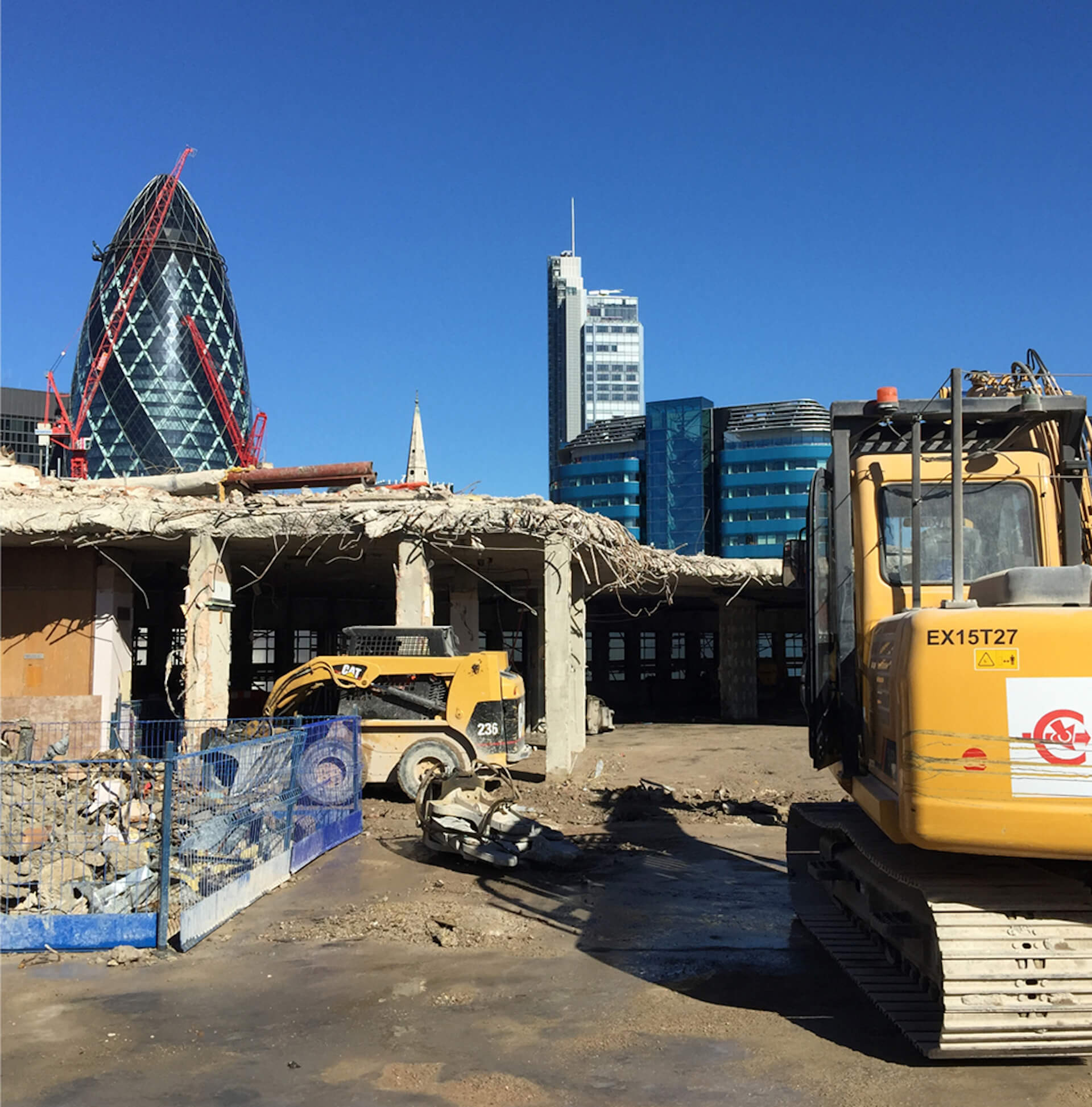 A demolition scene in the middle of a city. London office buildings in the background. construction machinery next to a partially demolished building.