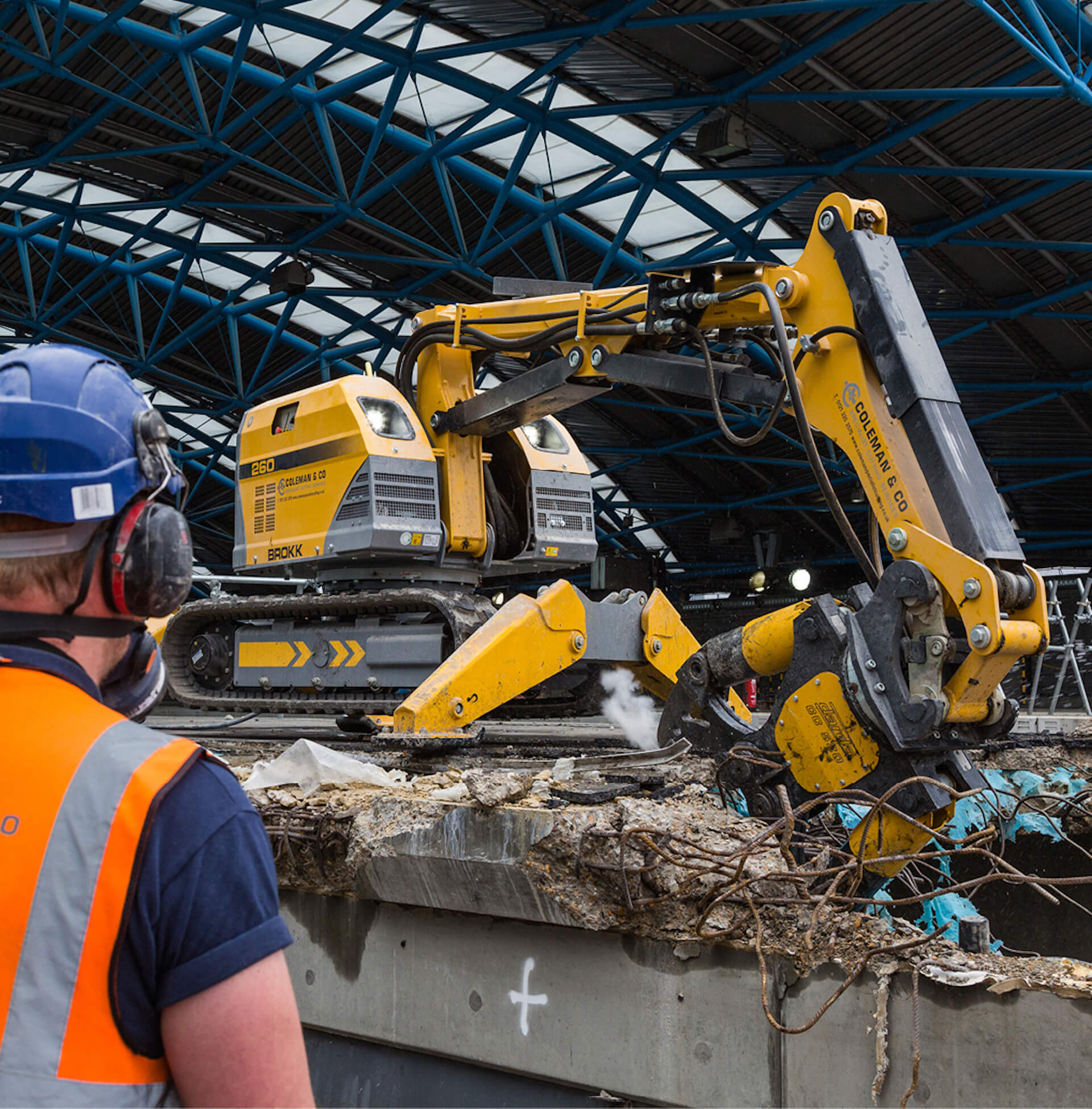 worker is operating a remote controlled Brokk machine being used to cut into a concrete and steel structure