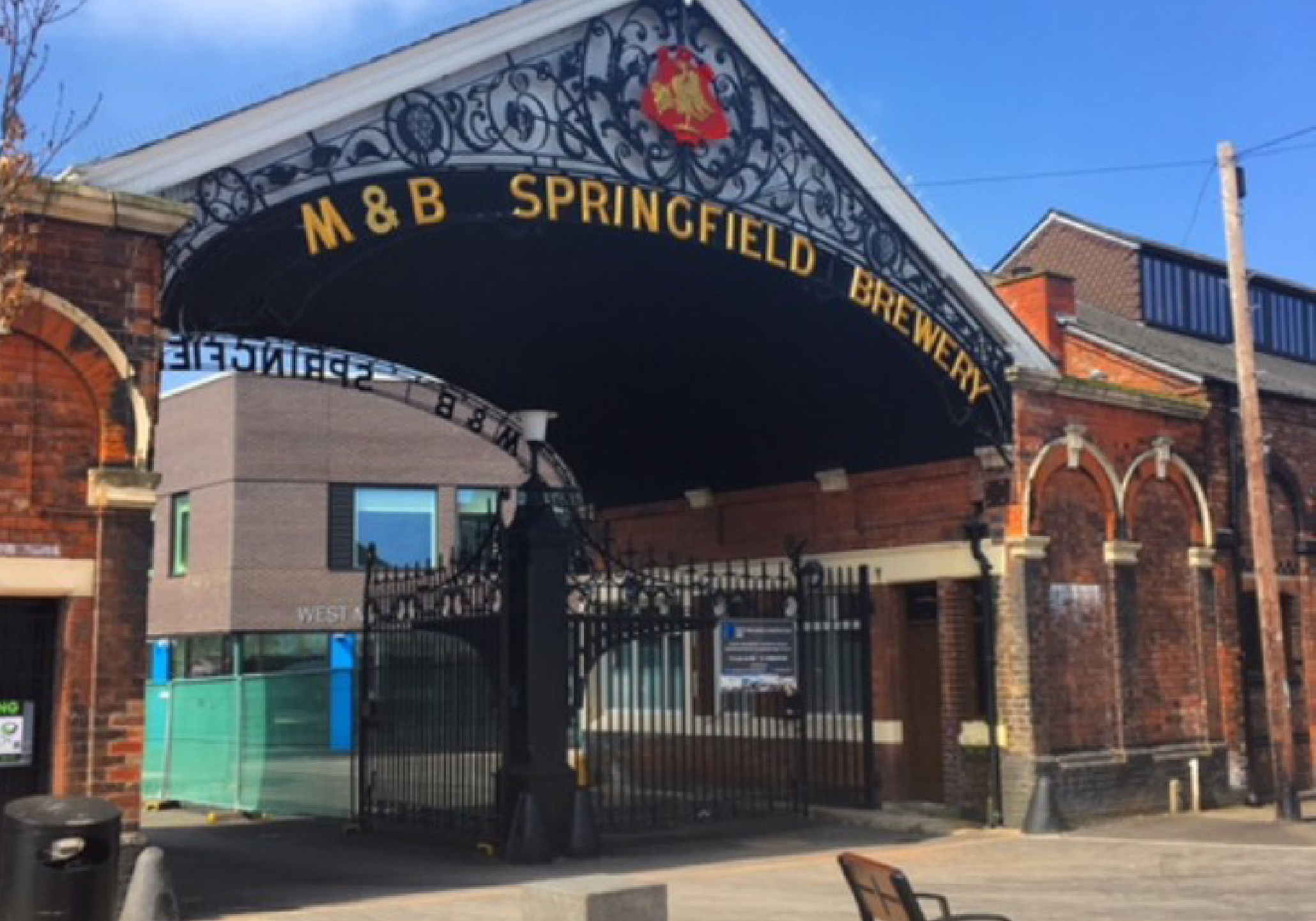 Entrance to Springfield brewery. Wrought iron black gates with ornate pitched roof above it.