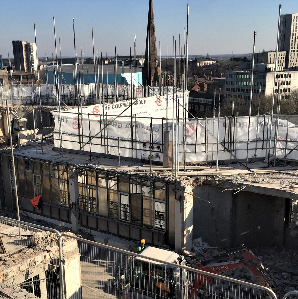 image of rooftop city landscape with deconstruction site in the foreground. Scaffolding with white protective sheeting containing colemans branding.