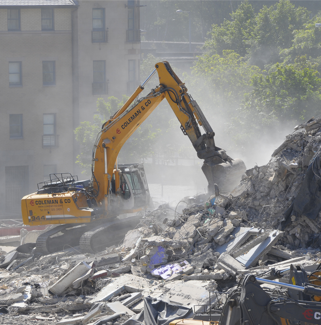 Remaining site materials being cleared by excavator after the explosive demolition of the two 24 storey tower blocks